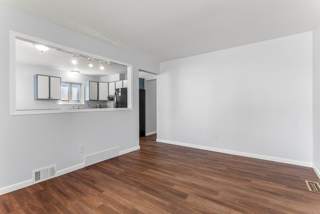 15945 Horger Ave, Allen Park, MI 48101 - unfurnished living room featuring track lighting, dark wood-style floors, and baseboards