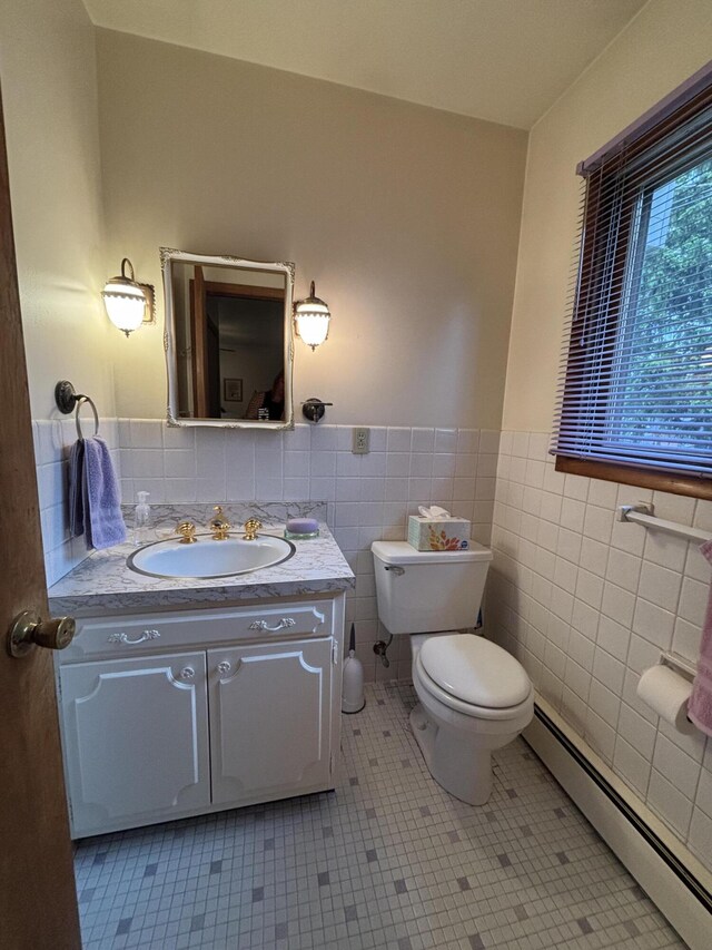 300 Maplecrest Ave, Sturgis, MI 49091 - bathroom featuring a baseboard heating unit, wainscoting, toilet, tile walls, and vanity