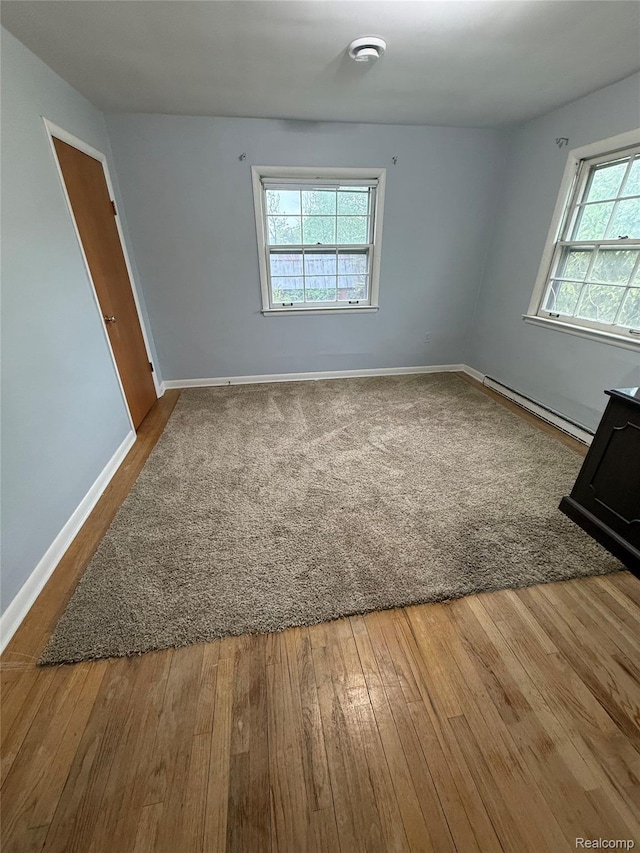 835 W Marr Rd, Howell, MI 48855 - empty room with a baseboard heating unit, hardwood / wood-style floors, and baseboards