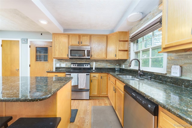 835 W Marr Rd, Howell, MI 48855 - kitchen with stainless steel appliances, a sink, light wood-style floors, dark stone counters, and tasteful backsplash