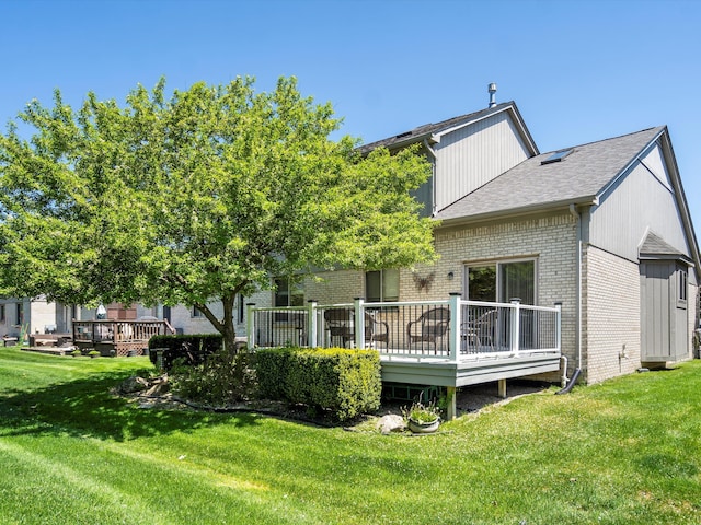 46311 Bentley Cir W Unit 51, Macomb, MI 48044 - rear view of house with a deck, brick siding, a lawn, and roof with shingles