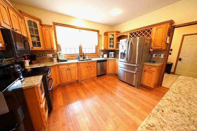 12161 Ladd Rd, Brooklyn, MI 49230 - kitchen featuring appliances with stainless steel finishes, a sink, decorative backsplash, light wood-style flooring, and glass insert cabinets