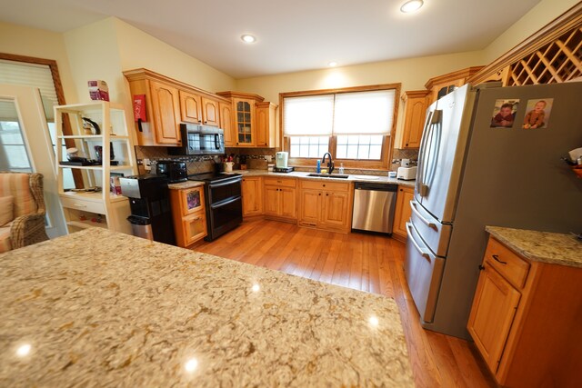 12161 Ladd Rd, Brooklyn, MI 49230 - kitchen featuring appliances with stainless steel finishes, a sink, light wood-type flooring, decorative backsplash, and light stone counters