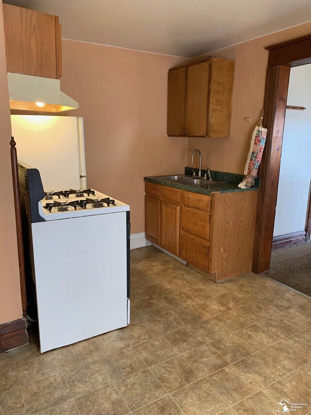 417 Harrison St, Monroe, MI 48161 - kitchen with white range with gas cooktop, a sink, brown cabinets, dark countertops, and under cabinet range hood