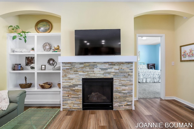 94 Cheyenne Ave, Holland, MI 49424 - living area with wood finished floors, a stone fireplace, built in shelves, arched walkways, and baseboards
