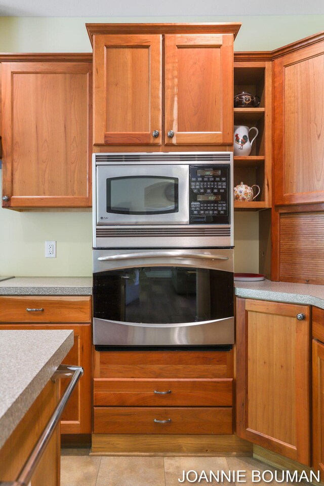 94 Cheyenne Ave, Holland, MI 49424 - kitchen with appliances with stainless steel finishes, light tile patterned floors, open shelves, light countertops, and brown cabinets