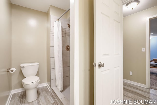 94 Cheyenne Ave, Holland, MI 49424 - bathroom featuring wood finished floors, toilet, a tile shower, and baseboards