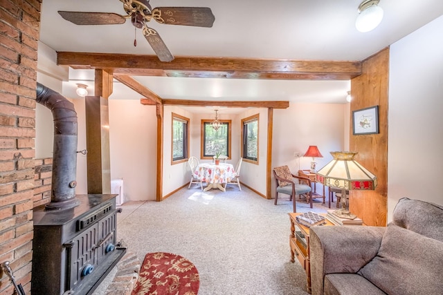 16545 Lonesome Trl, Leroy, MI 49655 - carpeted living room featuring a wood stove, beam ceiling, and a ceiling fan