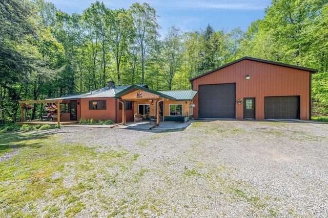 16545 Lonesome Trl, Leroy, MI 49655 - view of front facade featuring a chimney, a detached garage, metal roof, a porch, and a standing seam roof