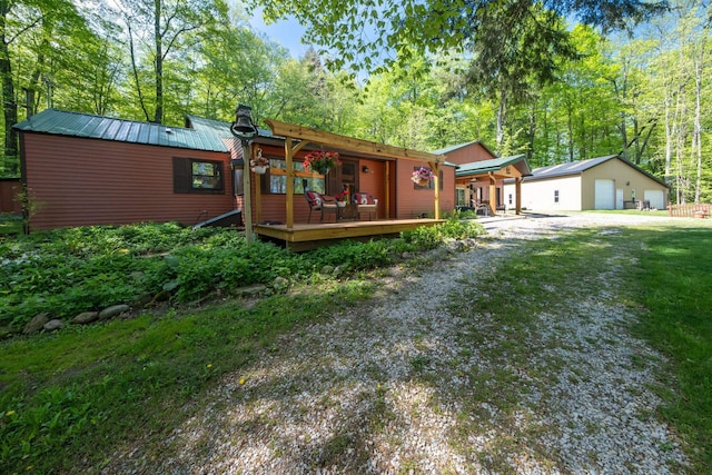 16545 Lonesome Trl, Leroy, MI 49655 - view of front of home featuring metal roof, a wooden deck, a chimney, a detached garage, and an outdoor structure
