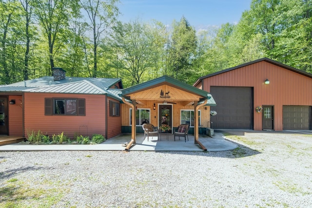 16545 Lonesome Trl, Leroy, MI 49655 - view of front of house featuring a chimney, a standing seam roof, a detached garage, metal roof, and an outbuilding