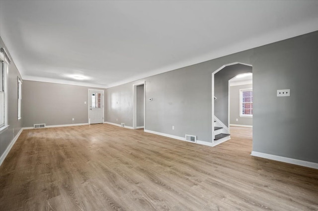18611 Pinehurst St, Detroit, MI 48221 - unfurnished room with arched walkways, baseboards, stairs, and light wood-type flooring