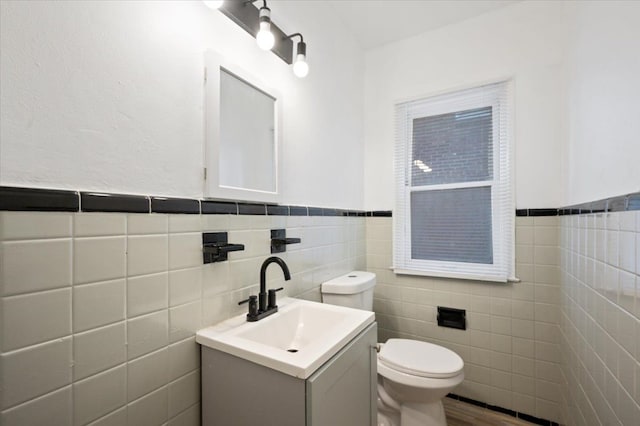 18611 Pinehurst St, Detroit, MI 48221 - bathroom with toilet, tile walls, vanity, wainscoting, and wood finished floors