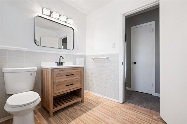 18611 Pinehurst St, Detroit, MI 48221 - half bathroom featuring tile walls, wood finished floors, toilet, vanity, and wainscoting