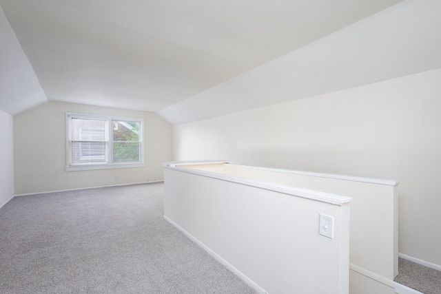 bonus room featuring light colored carpet, lofted ceiling, and baseboards