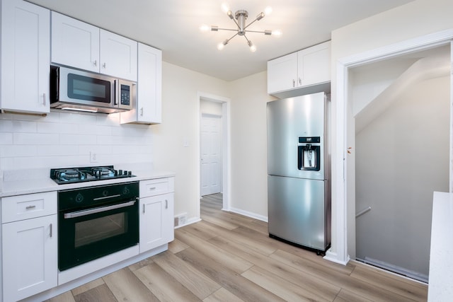 kitchen with appliances with stainless steel finishes, a chandelier, tasteful backsplash, light wood-type flooring, and light countertops