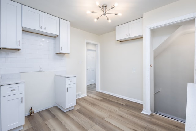 kitchen featuring a chandelier, light wood-style floors, light countertops, and white cabinetry