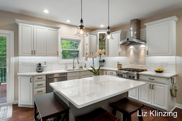 966 Timber Winds Dr SW, Grand Rapids, MI 49534 - kitchen with wall chimney range hood, stainless steel appliances, a sink, a breakfast bar area, and dark wood-type flooring