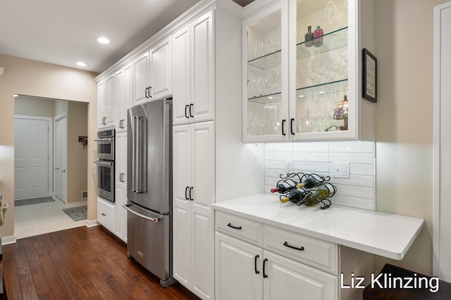 966 Timber Winds Dr SW, Grand Rapids, MI 49534 - kitchen featuring appliances with stainless steel finishes, white cabinets, dark wood-style flooring, glass insert cabinets, and light countertops