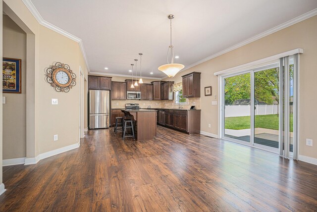 2380 Avalon Woods Dr, Portage, MI 49024 - kitchen featuring appliances with stainless steel finishes, a kitchen bar, dark brown cabinetry, crown molding, and a sink