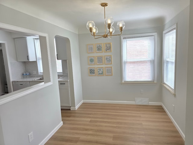 15360 Collinson Ave, Eastpointe, MI 48021 - unfurnished dining area with arched walkways, healthy amount of natural light, a chandelier, and light wood-style flooring