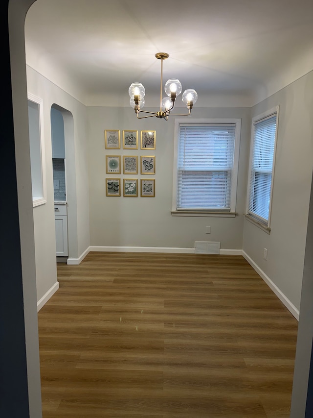 15360 Collinson Ave, Eastpointe, MI 48021 - unfurnished dining area with arched walkways, a chandelier, wood finished floors, and baseboards