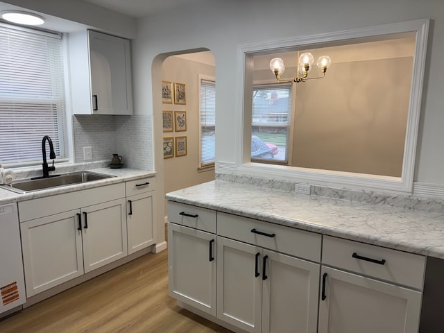 15360 Collinson Ave, Eastpointe, MI 48021 - kitchen with a sink, dishwasher, light wood finished floors, decorative backsplash, and arched walkways