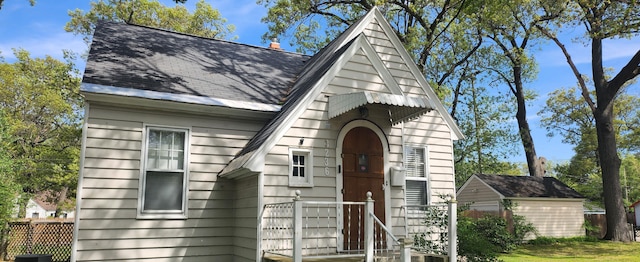 view of front of house featuring a shingled roof and fence