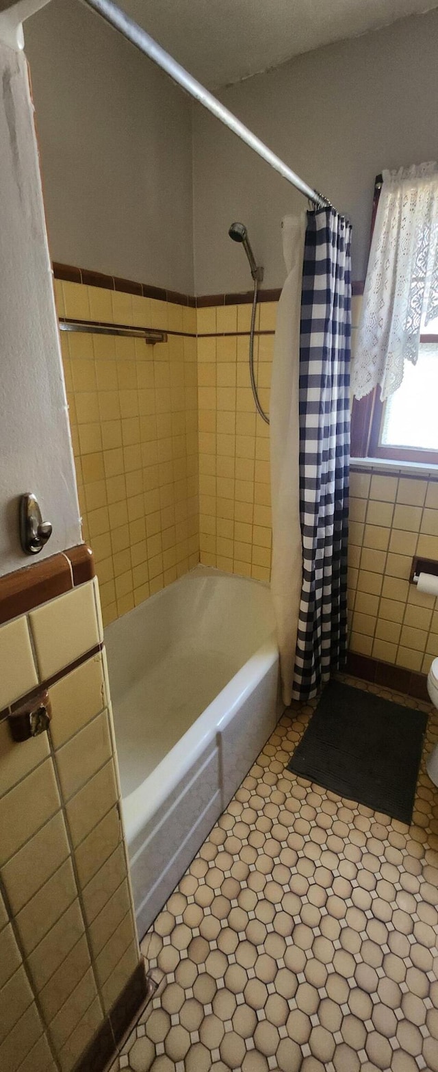 full bath featuring shower / bathtub combination with curtain, tile walls, and toilet