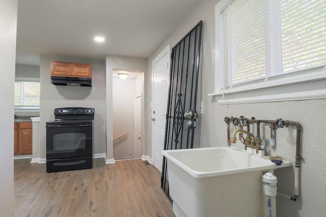 202 Haltiner St, River Rouge, MI 48218 - kitchen with black electric range, under cabinet range hood, a sink, brown cabinets, and light wood-type flooring