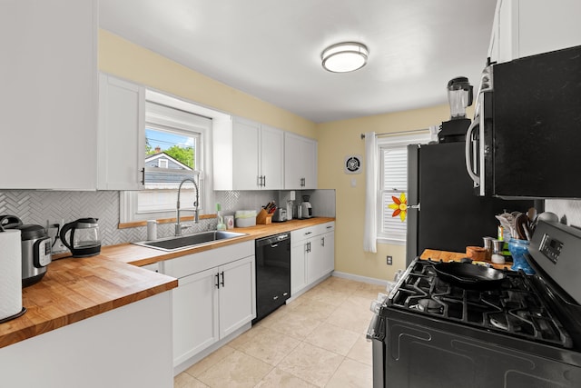 kitchen with appliances with stainless steel finishes, butcher block countertops, a sink, tasteful backsplash, and white cabinets