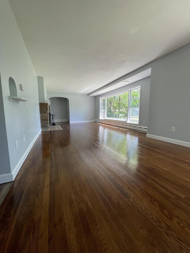 1648 Columbus Ave, Benton Harbor, MI 49022 - unfurnished living room with arched walkways, dark wood-style flooring, baseboards, and a baseboard heating unit