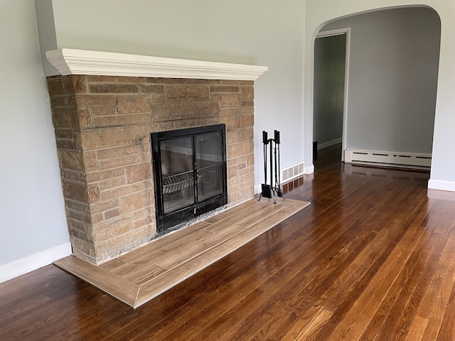 1648 Columbus Ave, Benton Harbor, MI 49022 - detailed view of a baseboard heating unit, a stone fireplace, arched walkways, baseboards, and wood finished floors