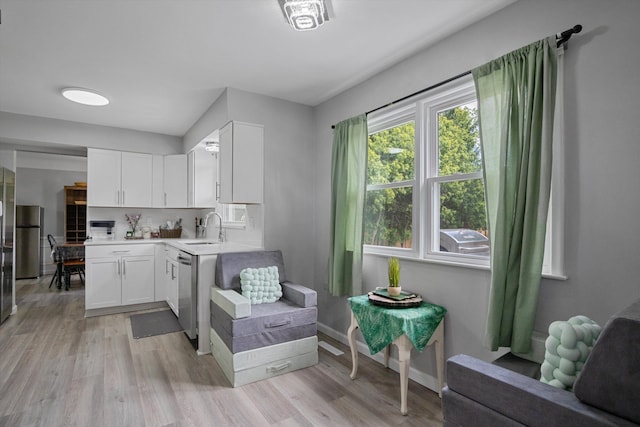 18441 Roseland Blvd, Lathrup Village, MI 48076 - kitchen with a sink, appliances with stainless steel finishes, light countertops, white cabinetry, and light wood finished floors