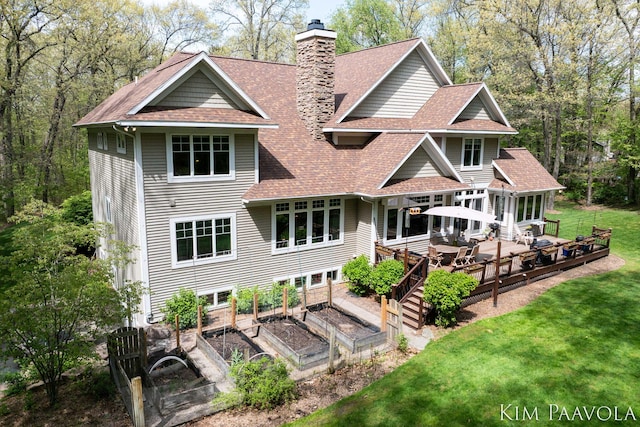 3099 Pickford Dr SE, Ada, MI 49301 - back of house with a garden, a chimney, roof with shingles, a yard, and a wooden deck