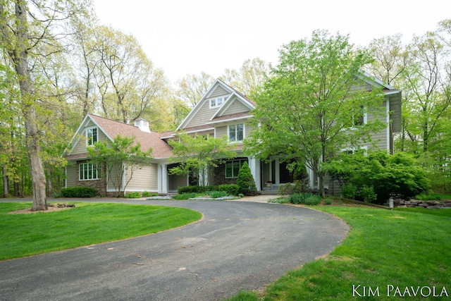 3099 Pickford Dr SE, Ada, MI 49301 - view of front of property with curved driveway, a front lawn, a shingled roof, and a chimney