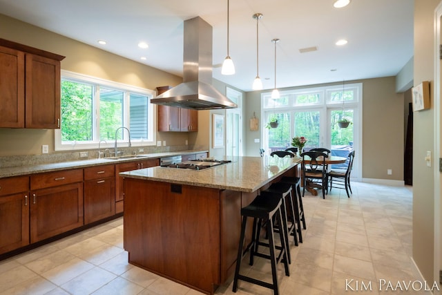 3099 Pickford Dr SE, Ada, MI 49301 - kitchen featuring a sink, island exhaust hood, a kitchen island, light stone counters, and a kitchen bar