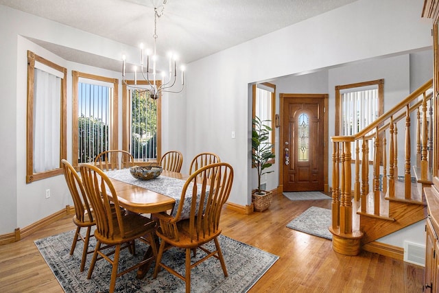 2512 Misty Ln, Davison, MI 48423 - dining room featuring a chandelier, baseboards, light wood-type flooring, and stairway