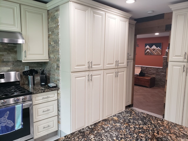 15701 Middlebelt Rd, Romulus, MI 48174 - kitchen featuring stainless steel gas range oven, under cabinet range hood, dark stone counters, a wainscoted wall, and recessed lighting