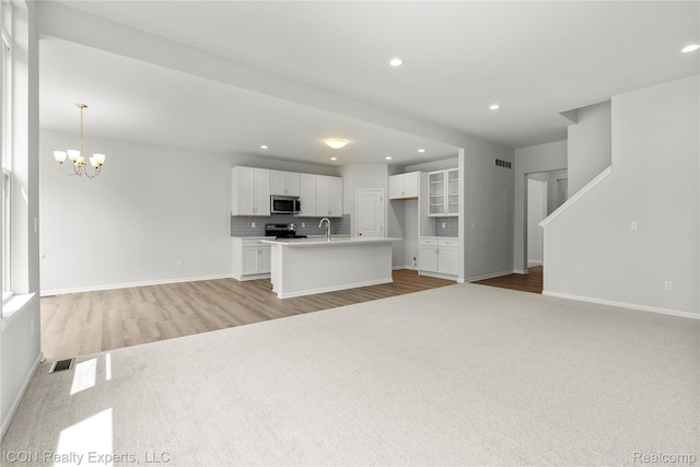 2396 Pondview Ln, Troy, MI 48085 - kitchen featuring appliances with stainless steel finishes, open floor plan, white cabinetry, a chandelier, and recessed lighting