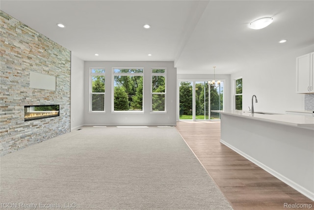 2396 Pondview Ln, Troy, MI 48085 - unfurnished living room with plenty of natural light, a chandelier, a stone fireplace, wood finished floors, and recessed lighting
