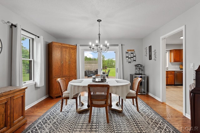 9705 Crescent Ct, Tecumseh, MI 49286 - dining area featuring a chandelier, light wood finished floors, baseboards, and a textured ceiling