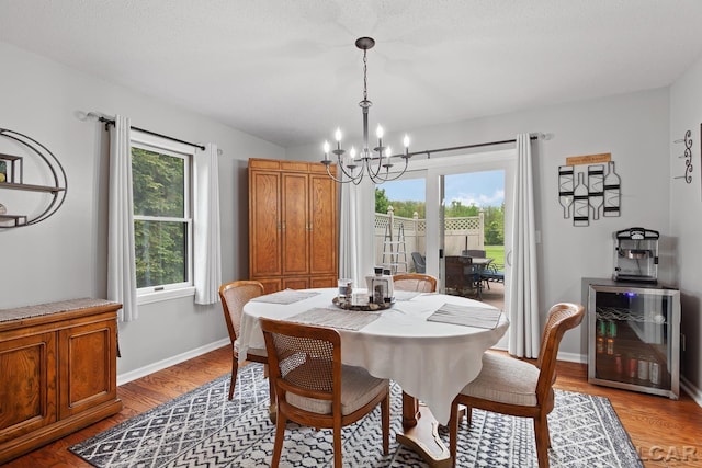 9705 Crescent Ct, Tecumseh, MI 49286 - dining room with wine cooler, a chandelier, light wood-type flooring, and baseboards