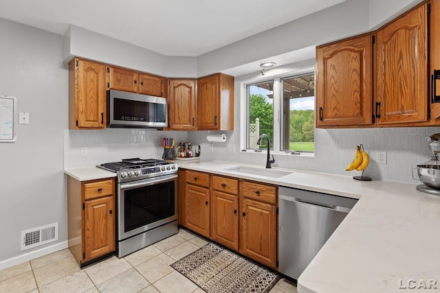 9705 Crescent Ct, Tecumseh, MI 49286 - kitchen with appliances with stainless steel finishes, a sink, light countertops, backsplash, and brown cabinets