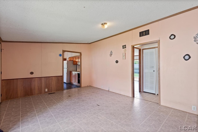 943 Howell Ave, Adrian, MI 49221 - empty room featuring crown molding, a textured ceiling, and wooden walls