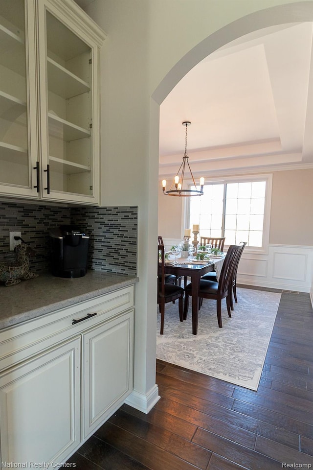 7118 Oak Ridge Ct, Clarkston, MI 48348 - dining area with arched walkways, dark wood finished floors, a chandelier, wainscoting, and a decorative wall