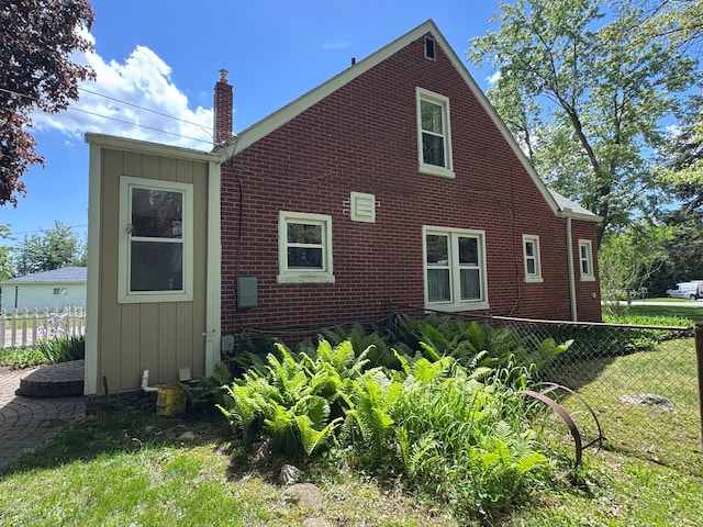 25220 Code Rd, Southfield, MI 48033 - view of side of home featuring board and batten siding, brick siding, and a chimney