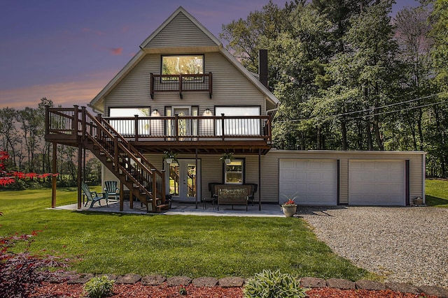 back of house at dusk featuring a wooden deck, driveway, a yard, a balcony, and stairway