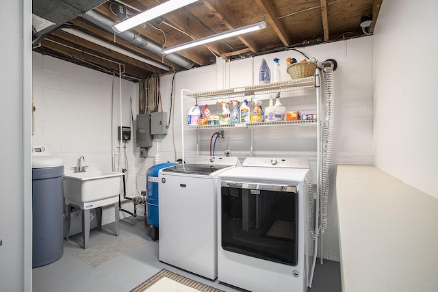 laundry area featuring washer and dryer, concrete block wall, and electric panel