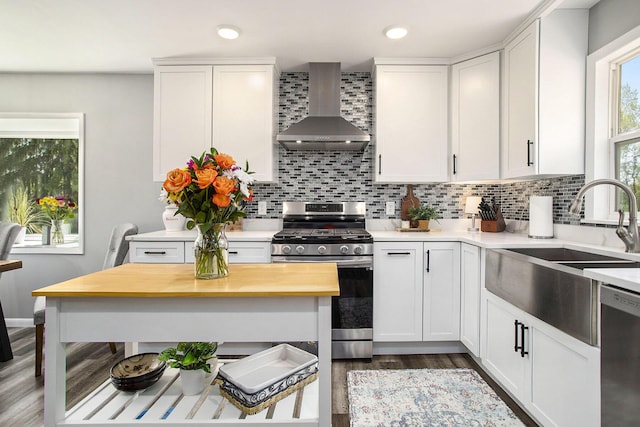 kitchen with wall chimney range hood, appliances with stainless steel finishes, a sink, backsplash, and recessed lighting